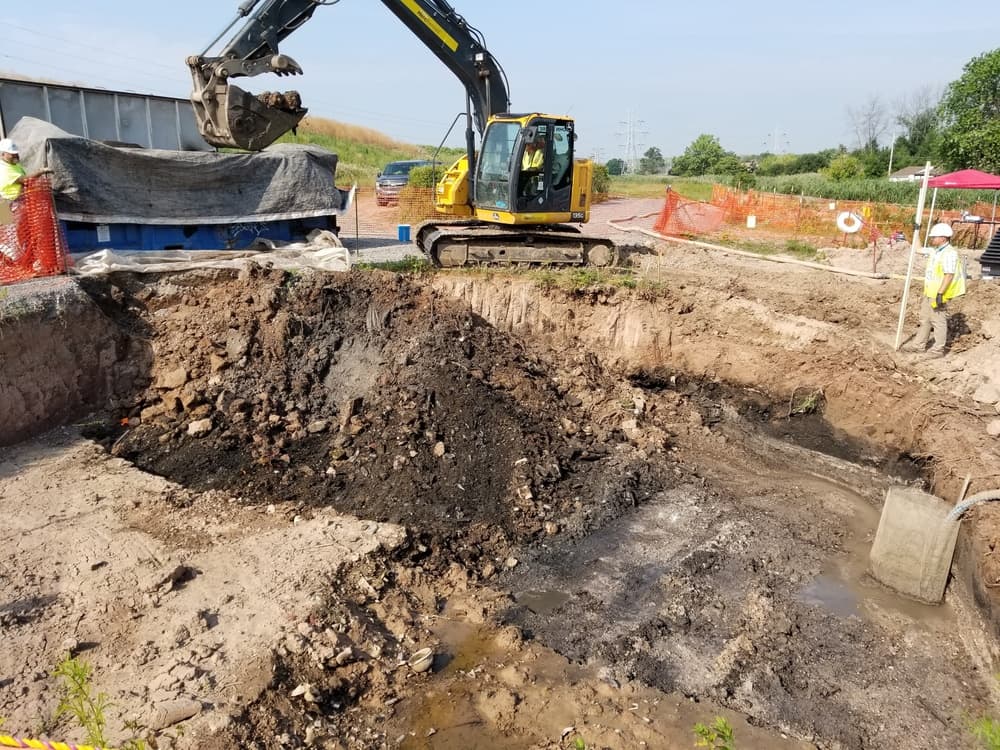 Excavator and field crew removing shallow contaminated soil at the Tonawanda Landfill FUSRAP vicinity property